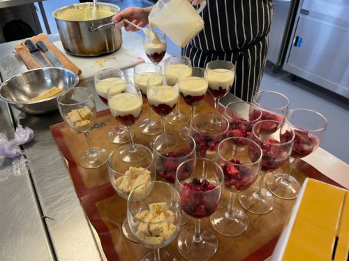 Students pouring custard into the trifle