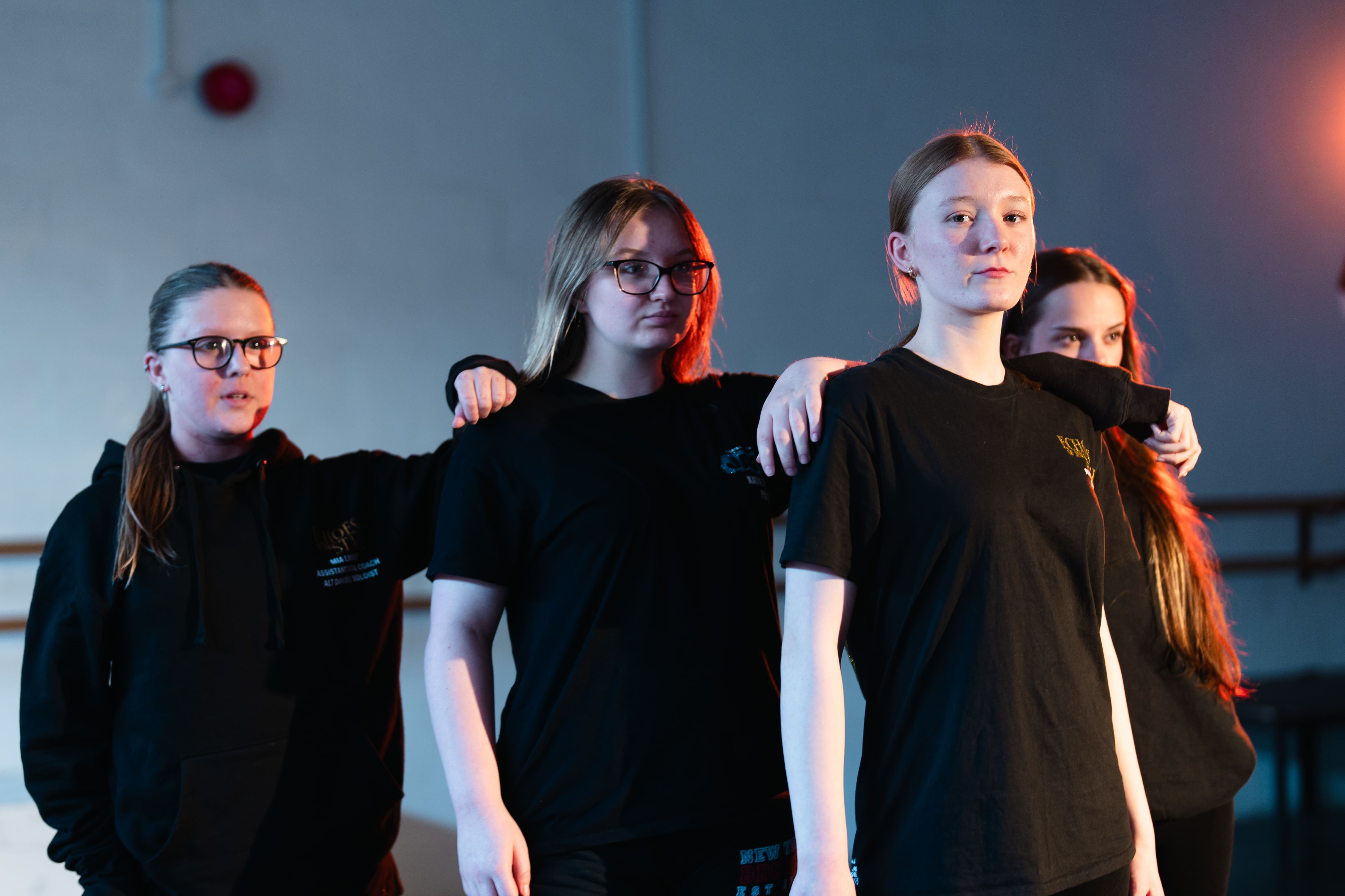 students in a perfromace stance with their arms on the others shoulder